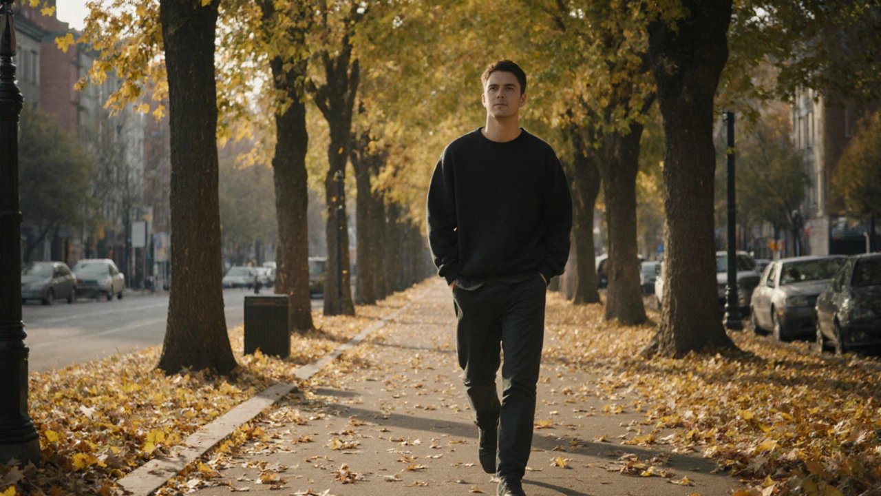 Osoba prochází listnatou ulicí v podzimním světle, klidně a bez telefonu.